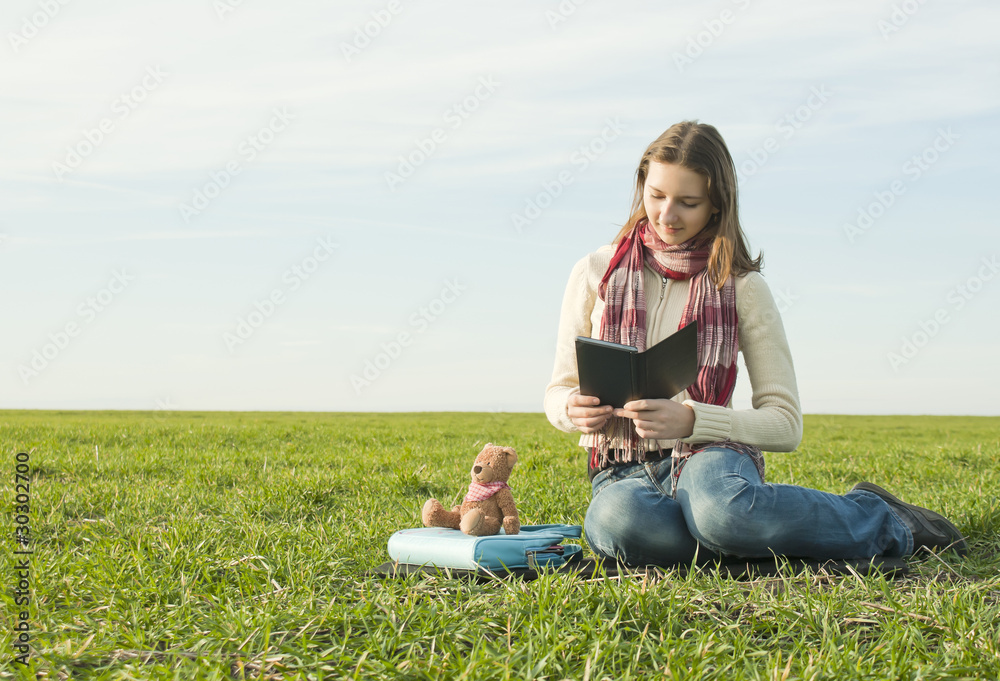 Girl reading a ebook sitting at grass