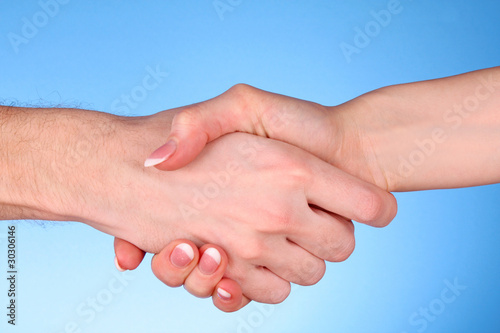 handshake between man and woman on blue background © Africa Studio