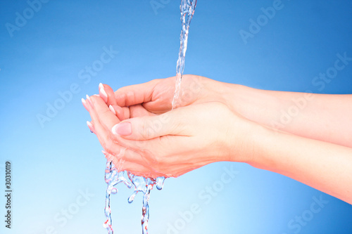 Human hands with water splashing on them with blue background