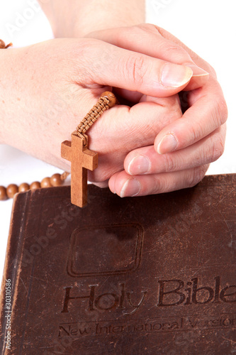 Person holding cross on bible photo