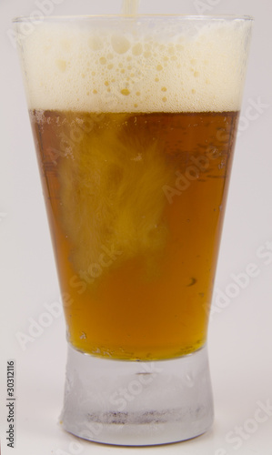 Frosty glass of cold beer being poured