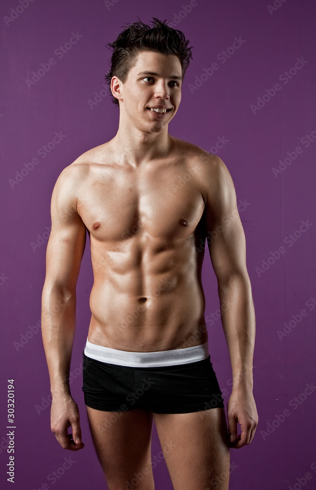Fototapeta premium Sexy muscle wet young man on purple background