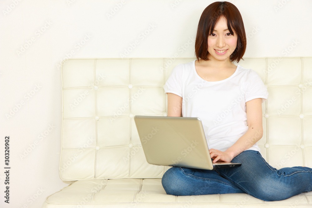 young women on white couch relaxing and using laptop computer young women on white couch relaxing and using laptop computer