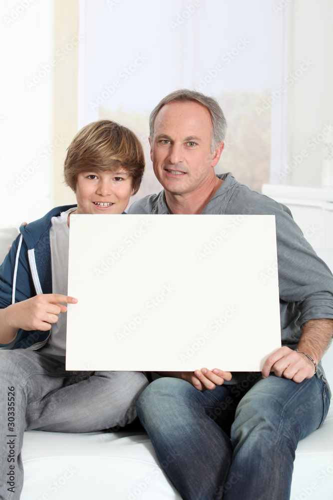 Man and young boy holding white message board Man and young boy holding white message board