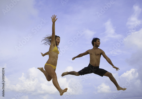 young couple jumping in the air at a hawaii beach