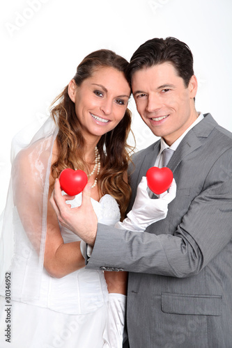 Bride and groom holding red hearts on white background