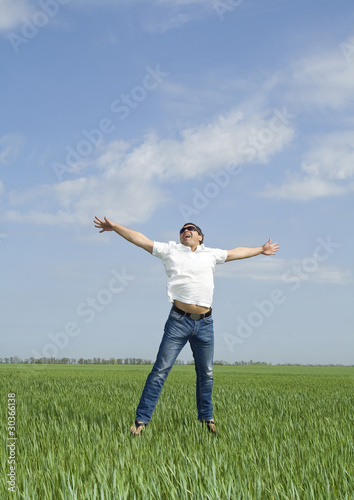 young man jumping a green field of grass
