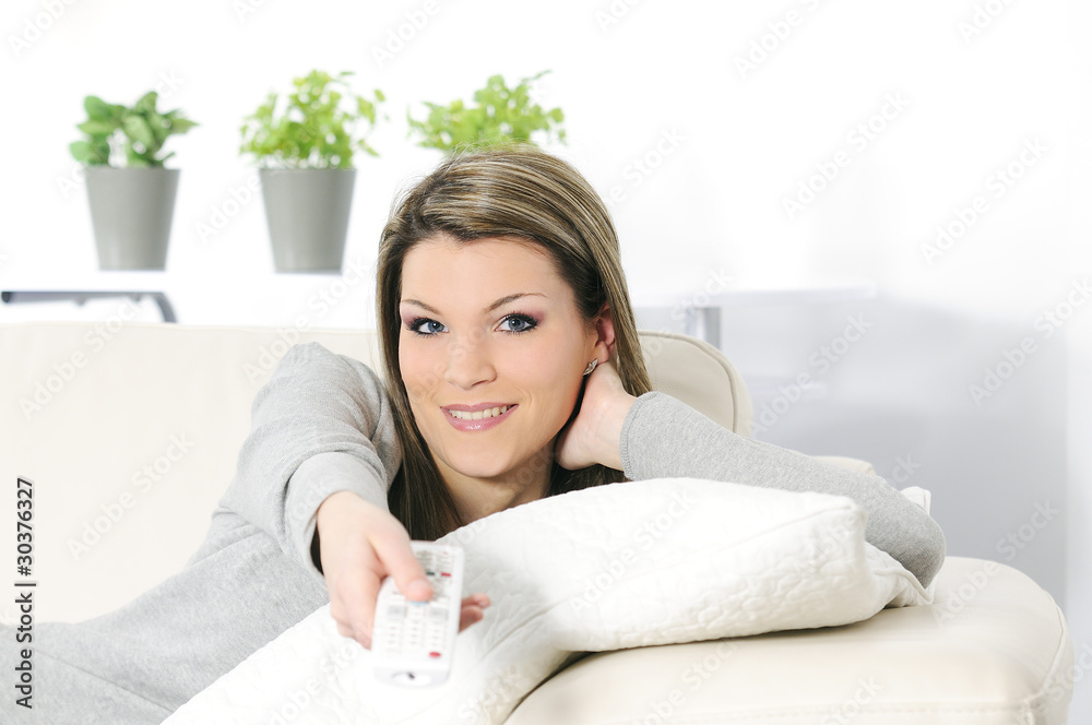 young woman in her sofa activating a remote control TV young woman in her sofa activating a remote control TV
