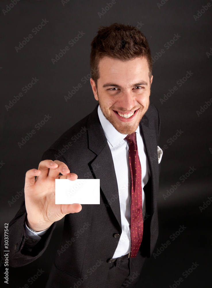 Businessman showing a businesscard, dark background Businessman showing a businesscard, dark background