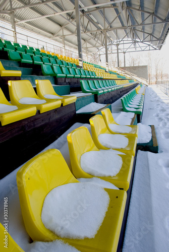 football stadium tribune yelow and green chairs in winter photo