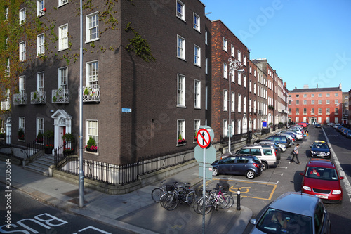 Canvas Print four-story house stands beside road, windows, car on crossroad