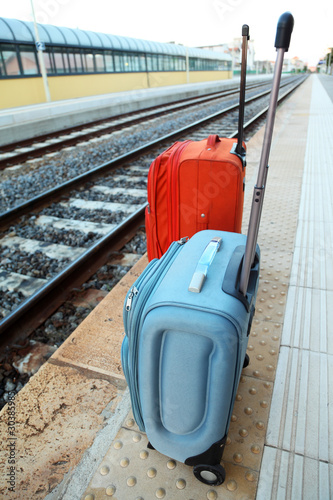 two big travel bags stands on platform near railway tracks