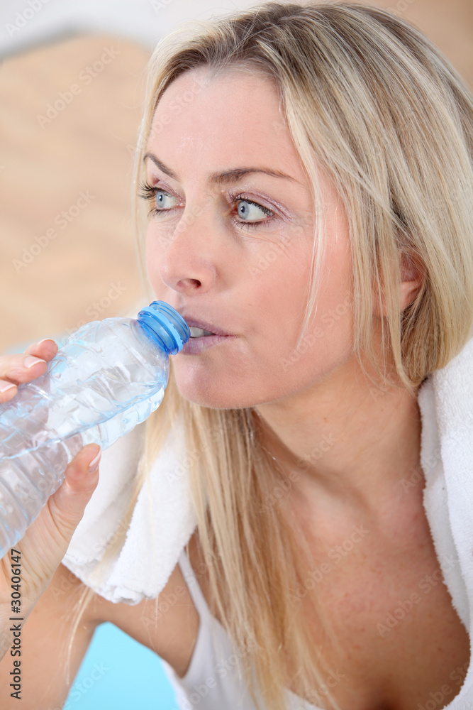 Beautiful blond woman drinking water after exercising Beautiful blond woman drinking water after exercising