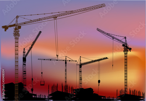 cranes above buildings at sunset