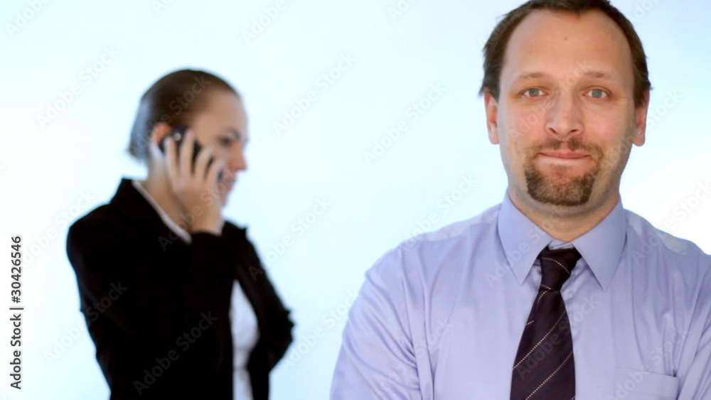 Businessman looking to the camera, businesswoman in background Businessman looking to the camera, businesswoman in background