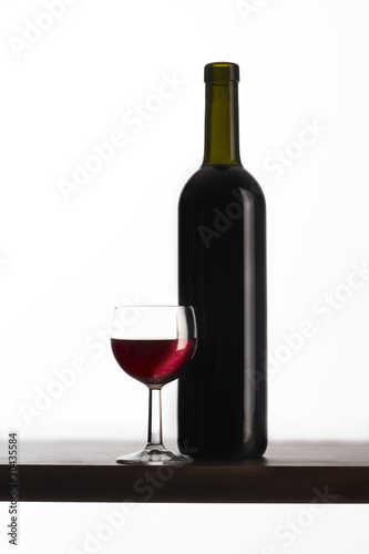 Bottiglia di vino rosso con bicchiere su fondo bianco