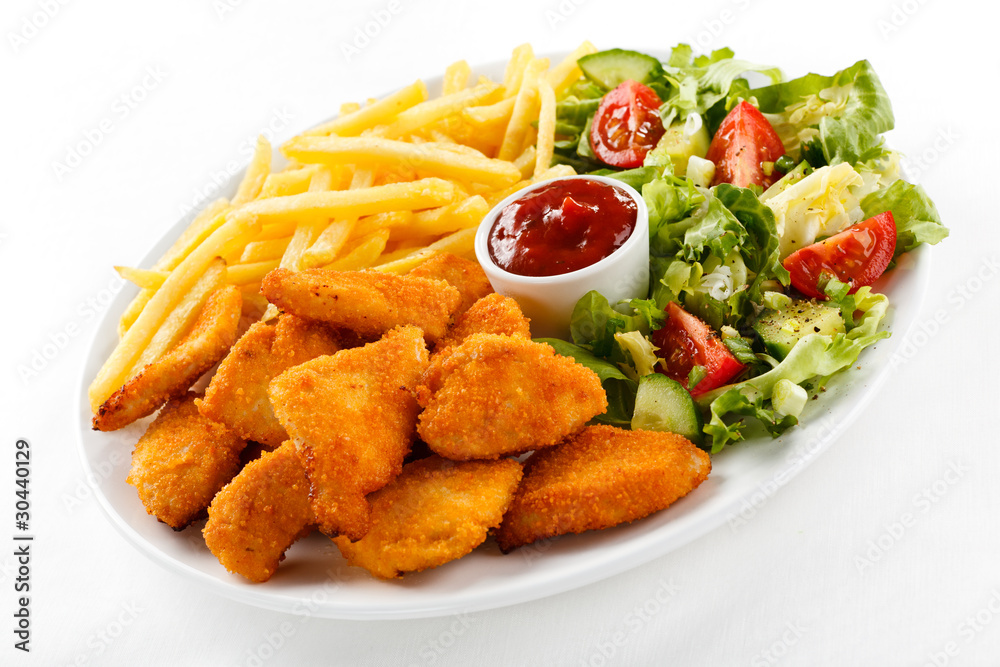 Fried chicken nuggets, French fries and vegetables Fried chicken nuggets, French fries and vegetables
