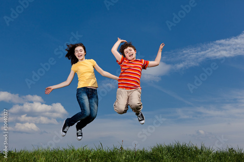 Girl and boy jumping, running against blue sky © Jacek Chabraszewski