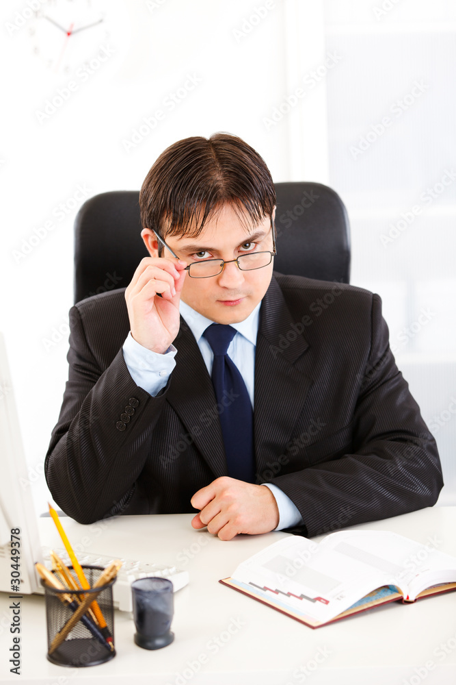 Authoritative businessman straightening eyeglasses. Authoritative businessman straightening eyeglasses.