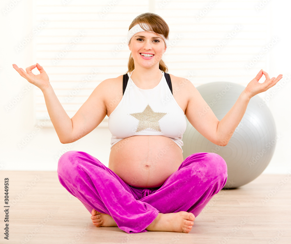 Smiling beautiful pregnant woman doing yoga on floor at room. Smiling beautiful pregnant woman doing yoga on floor at room.
