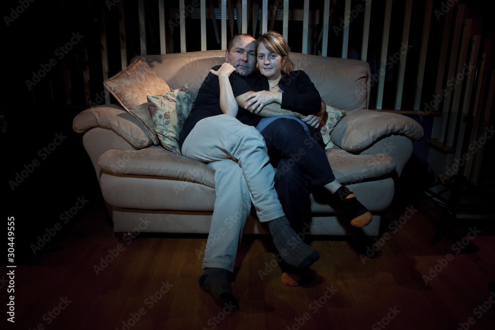 Happy couple sitting on a couch watching TV