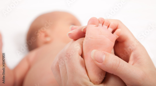 Mother's hands massaging little baby's foot