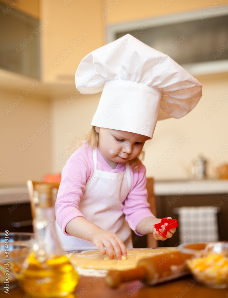 Little girl cuts dough for cookies on kitchen with form Little girl cuts dough for cookies on kitchen with form