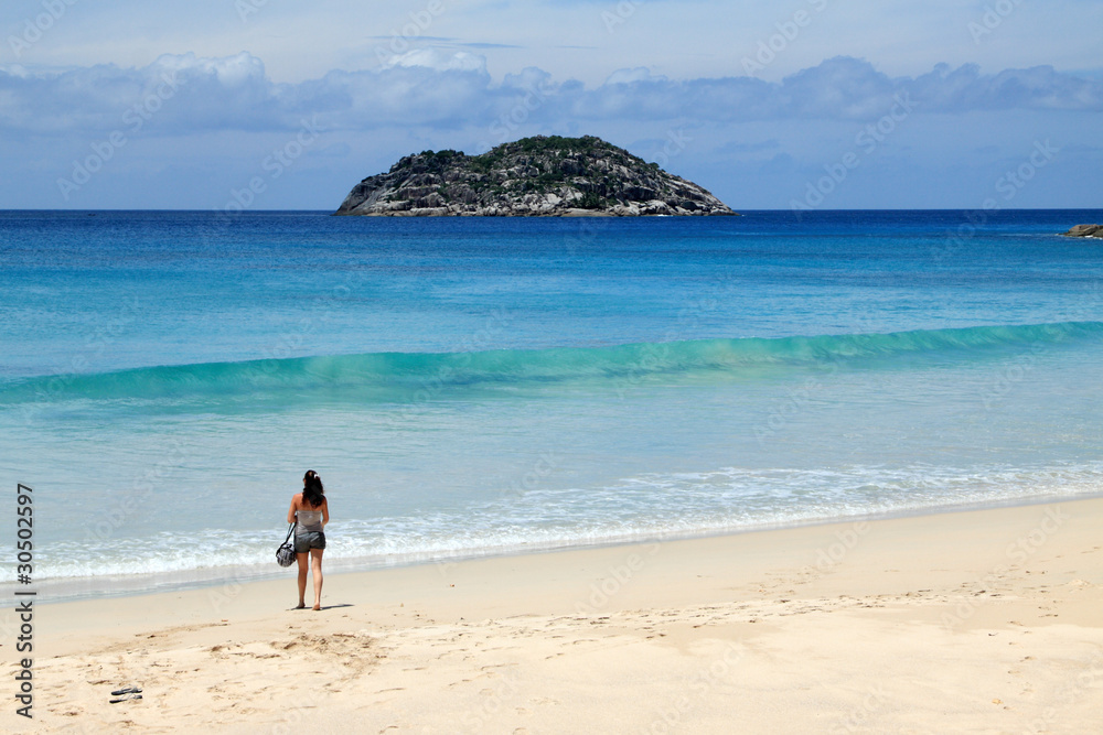 jeune femme sur plage de sable blanc aux Seychelles