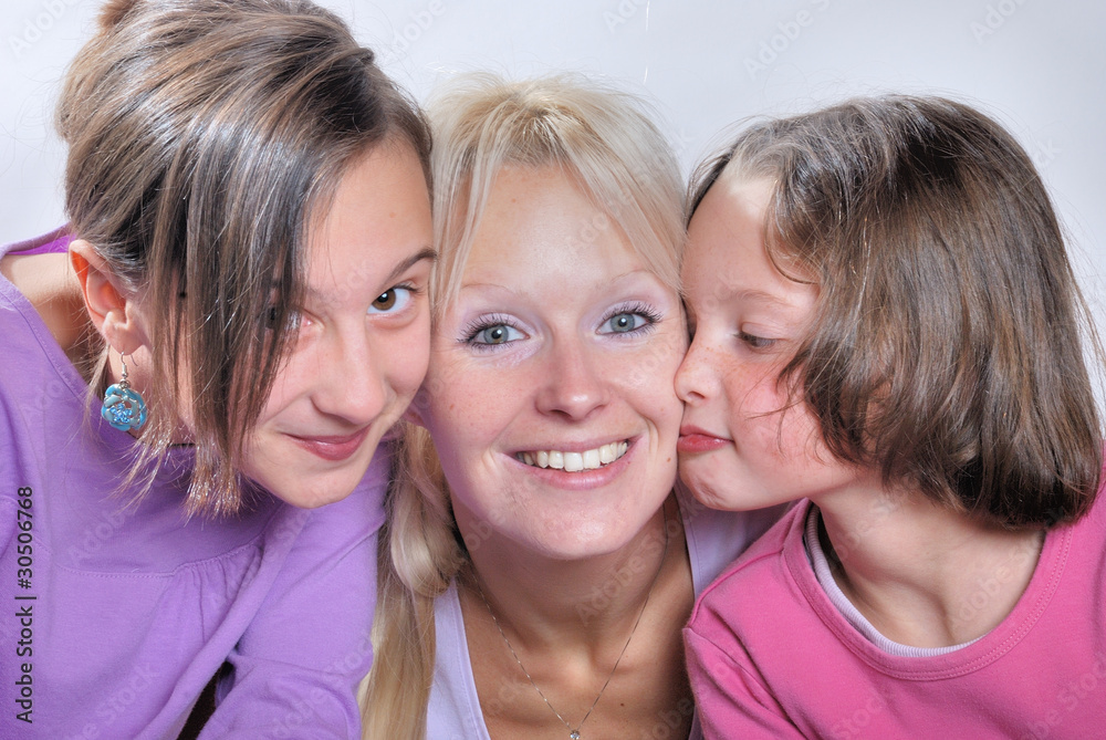 A mother smiles as she receives a kiss on the cheek from her you