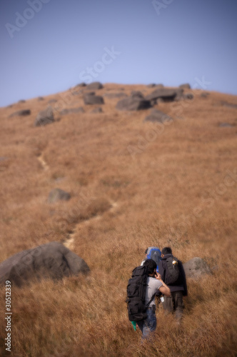 3 people hiking on a mountain full of brown grasses