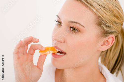 Healthy lifestyle - portrait of woman bite slice of tangerine
