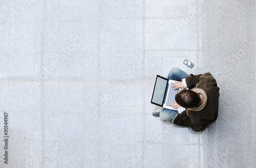 Young man sitting on the floor and  surfing on laptop photo