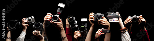 Raised hands holding different photocameras photo