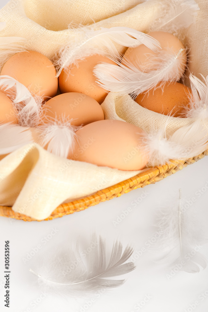 Macro of brown eggs and feathers in wooden basket Macro of brown eggs and feathers in wooden basket