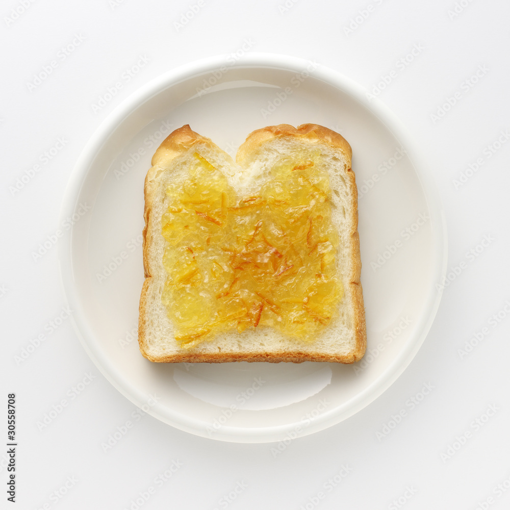 Slice of bread with marmalade on white dish Slice of bread with marmalade on white dish