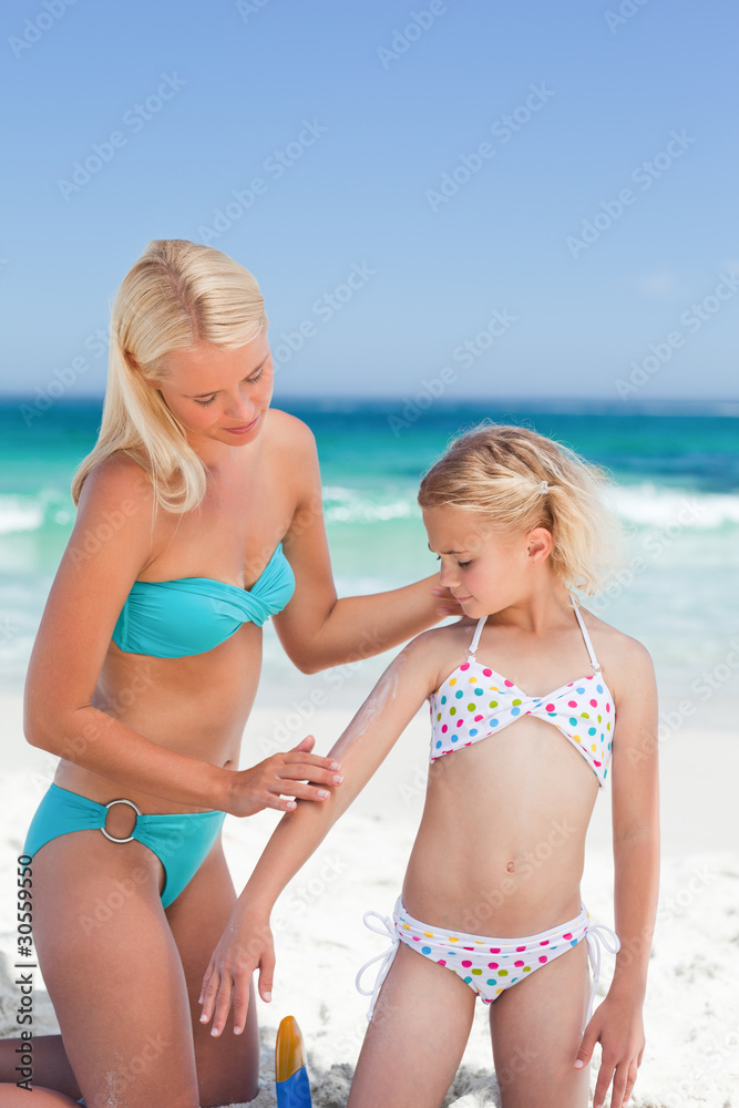 Mother applying sun cream on her daughter's back Mother applying sun cream on her daughter's back