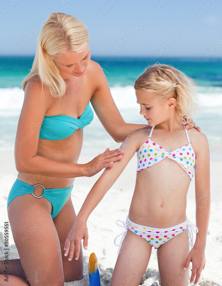 Mother applying sun cream on her daughter's back