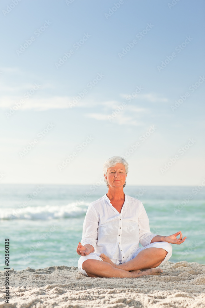 Mature woman practicing yoga on the beach Mature woman practicing yoga on the beach