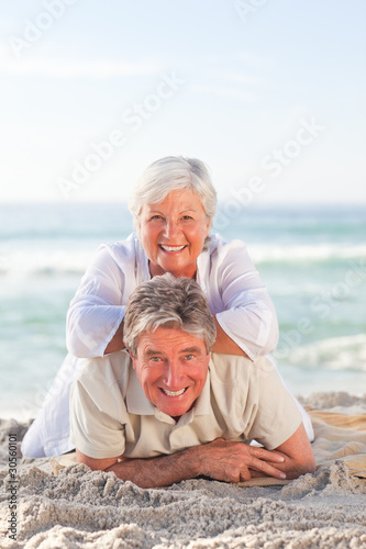 Elderly couple lying down on the beach