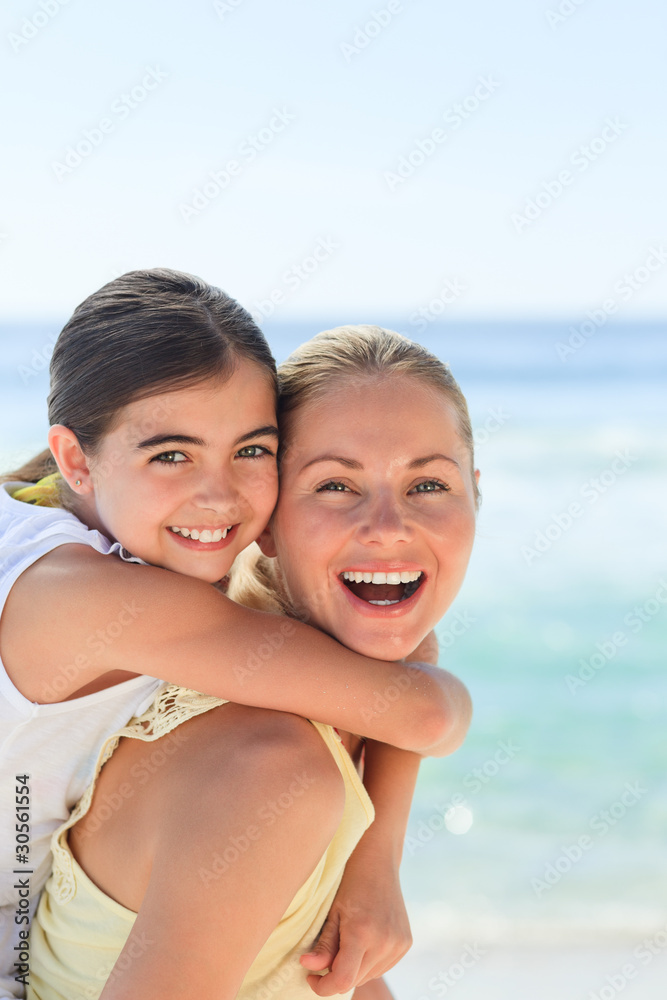 Mother having daughter a piggyback at the beach