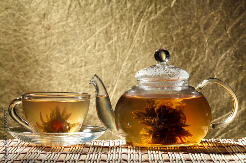 Glass teapot and a cup of green tea on a gold background