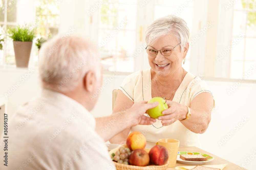 Laughing senior wife getting apple from husband