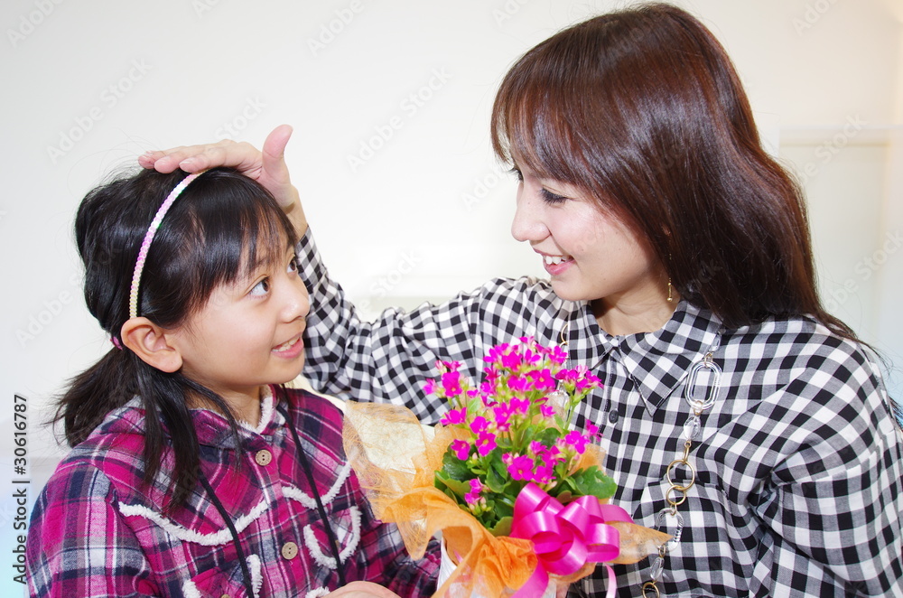 花のプレゼントを持った女の子と笑顔の母親 花のプレゼントを持った女の子と笑顔の母親