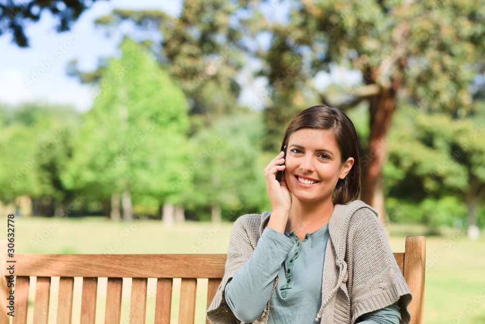 Young woman phoning on the bench