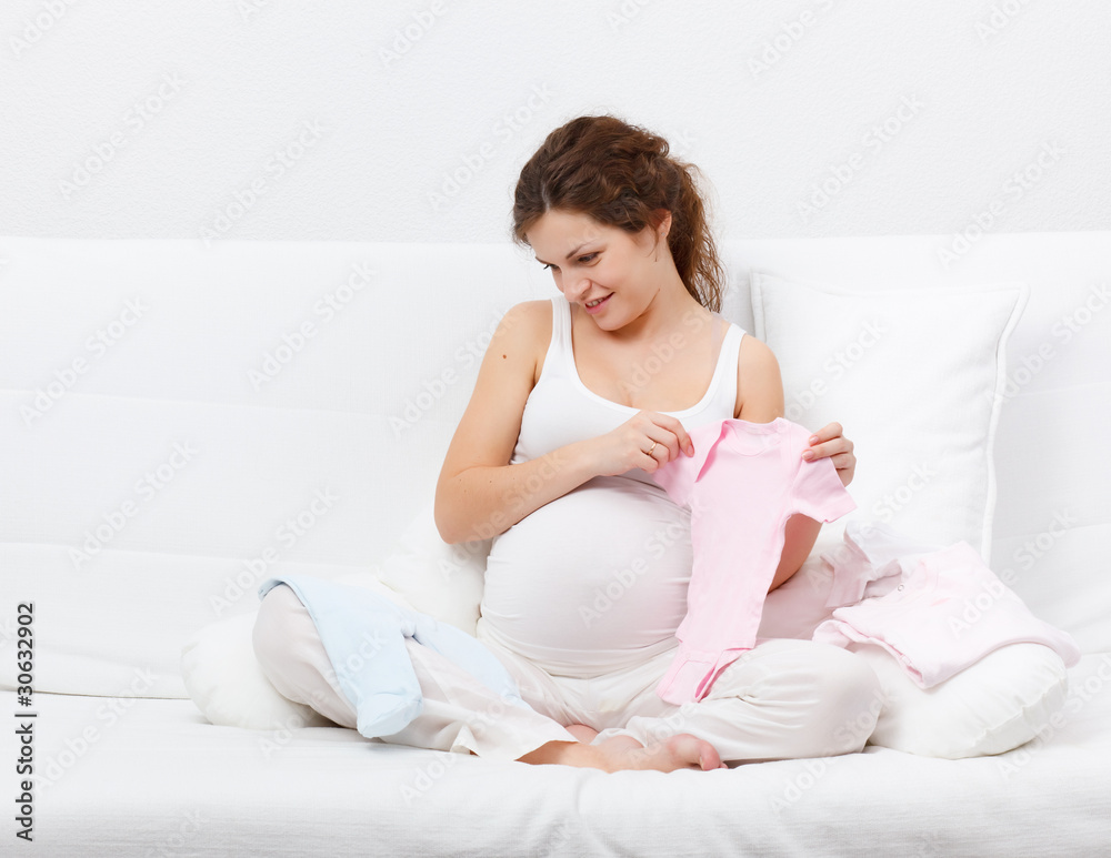 Beautiful pregnant woman choosing baby's clothes Beautiful pregnant woman choosing baby's clothes