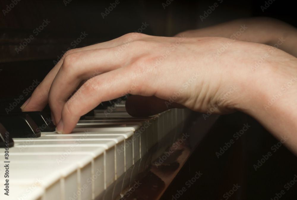 Fototapeta premium Child's hand playing on piano keyboard