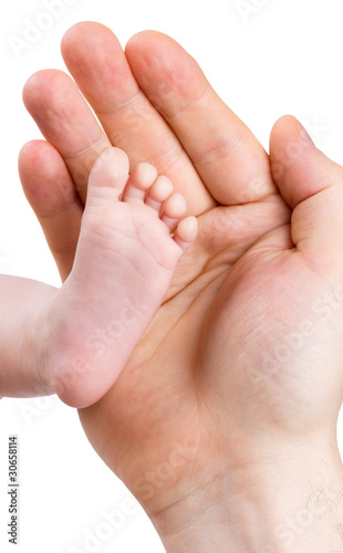 Small leg of the newborn baby girl in the big hand of the father