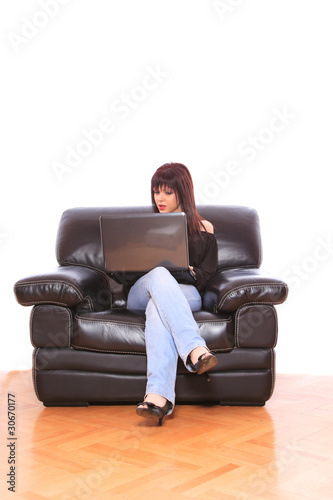 Young woman on couch and working on laptop