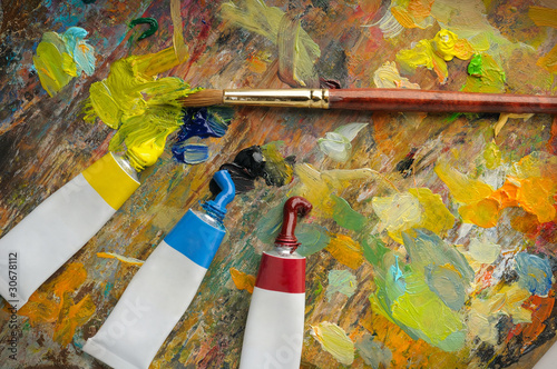Art tools. Multicolored artist s palette with spots of paint  brush and tubes of paint