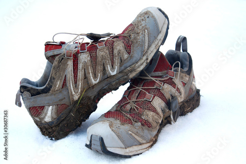 Muddy trail running shoes on white background